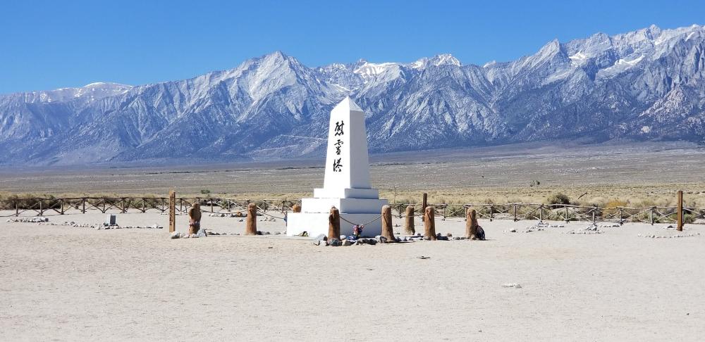 A few old wreaths of origami cranes adorned the cemetery in this photograph, some of which had blown off into the browning grass and scattered wildflowers.