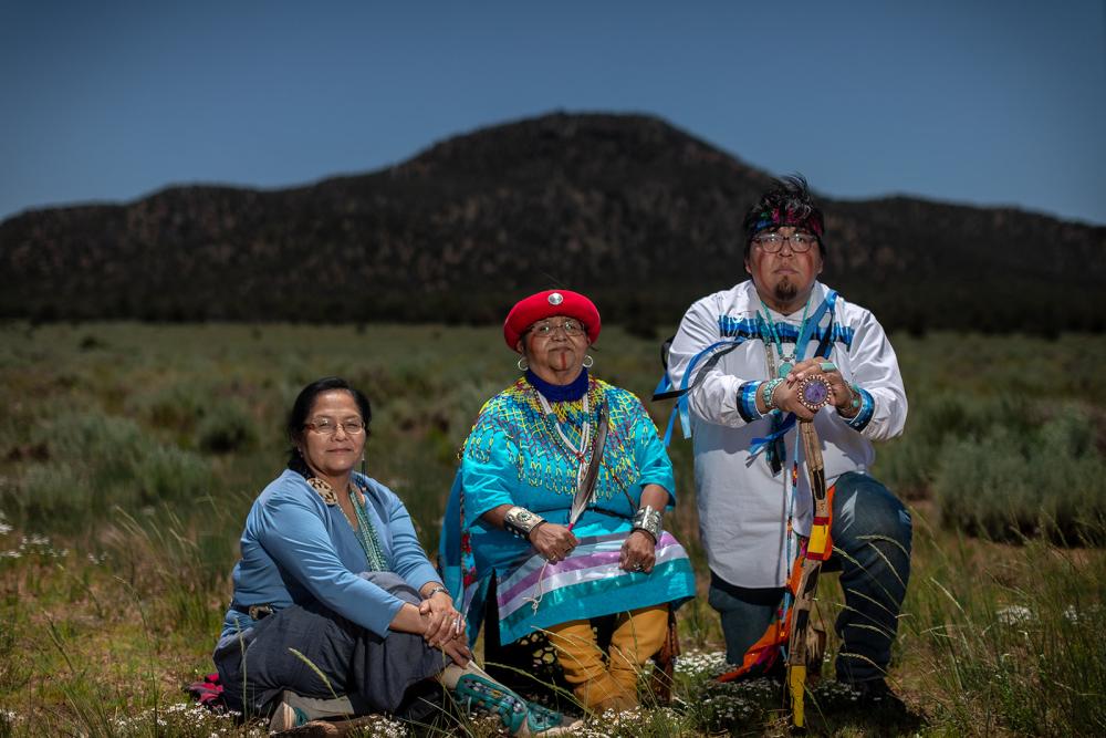 Portrait of three Indigenous peoples with mountain in the background.
