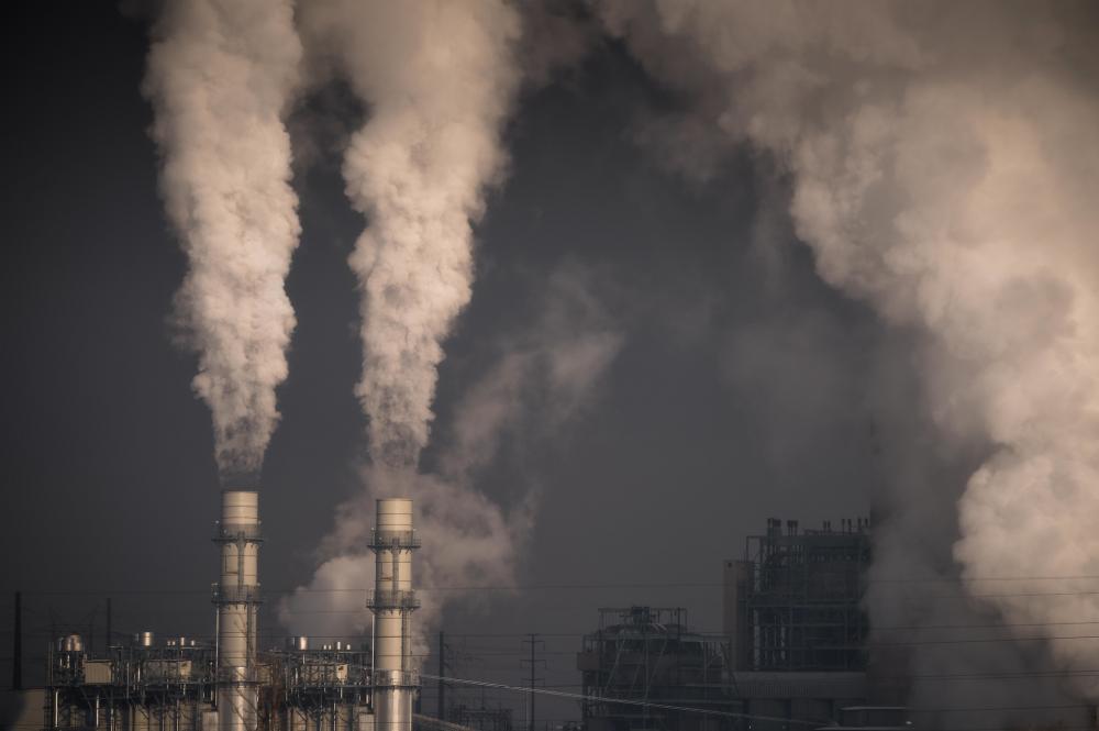 Smoke pouring out of two industrial smokestacks against a gray sky at Cherokee Generating Station