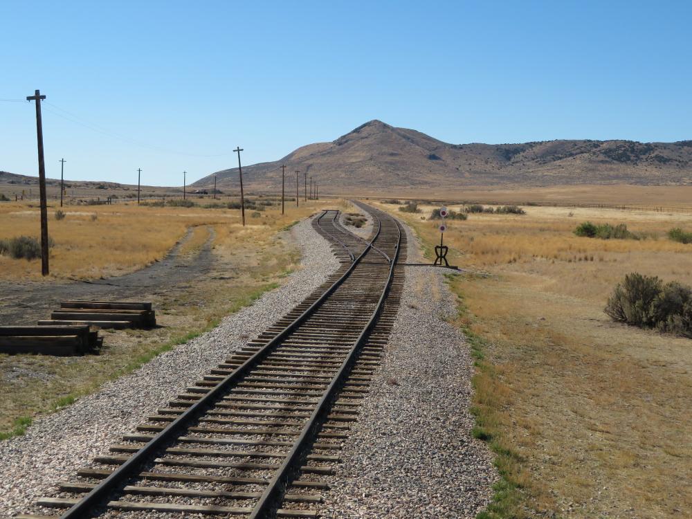 Train tracks disappearing on a vast landscape of mountains and savannah.