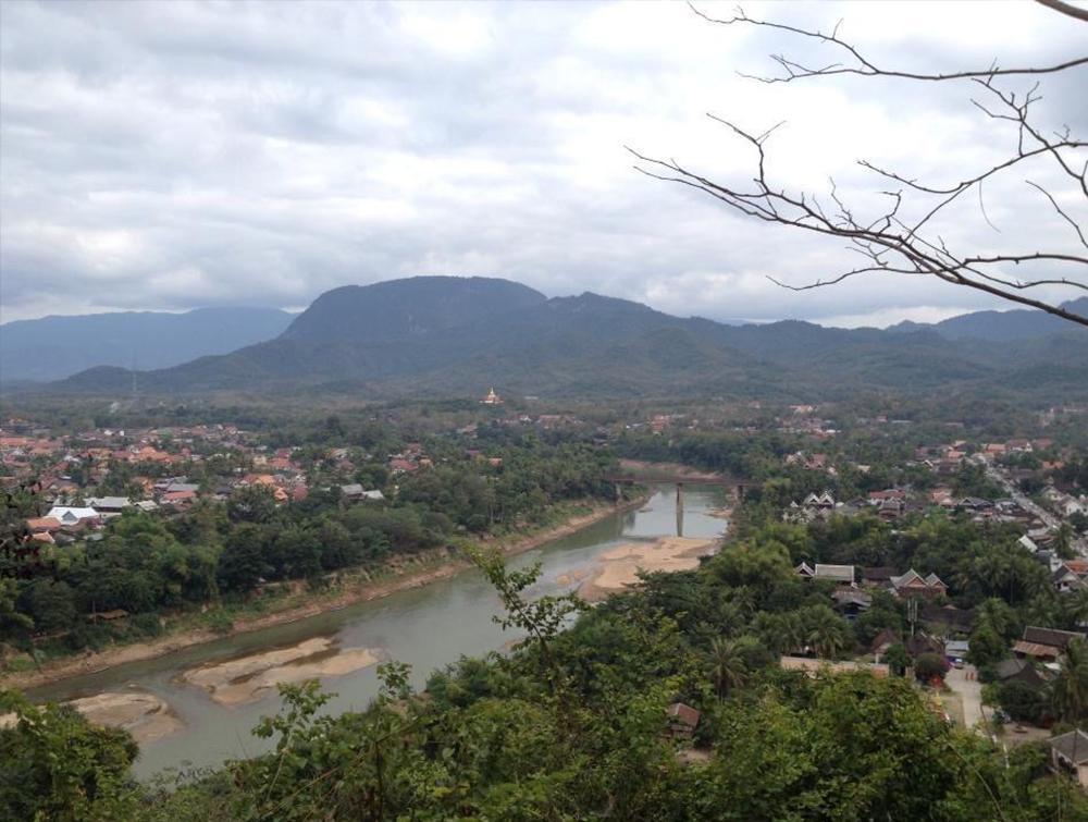 A lush mountain overlooks a town on an overcast day