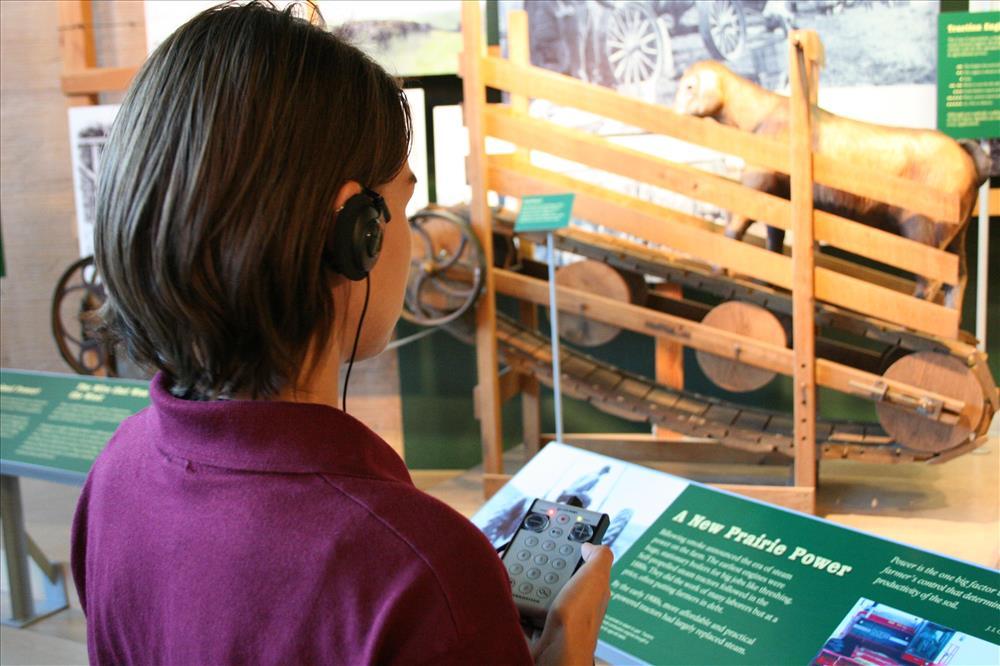 Person holding an audio description device to enjoy the displays at Homestead Heritage Center.