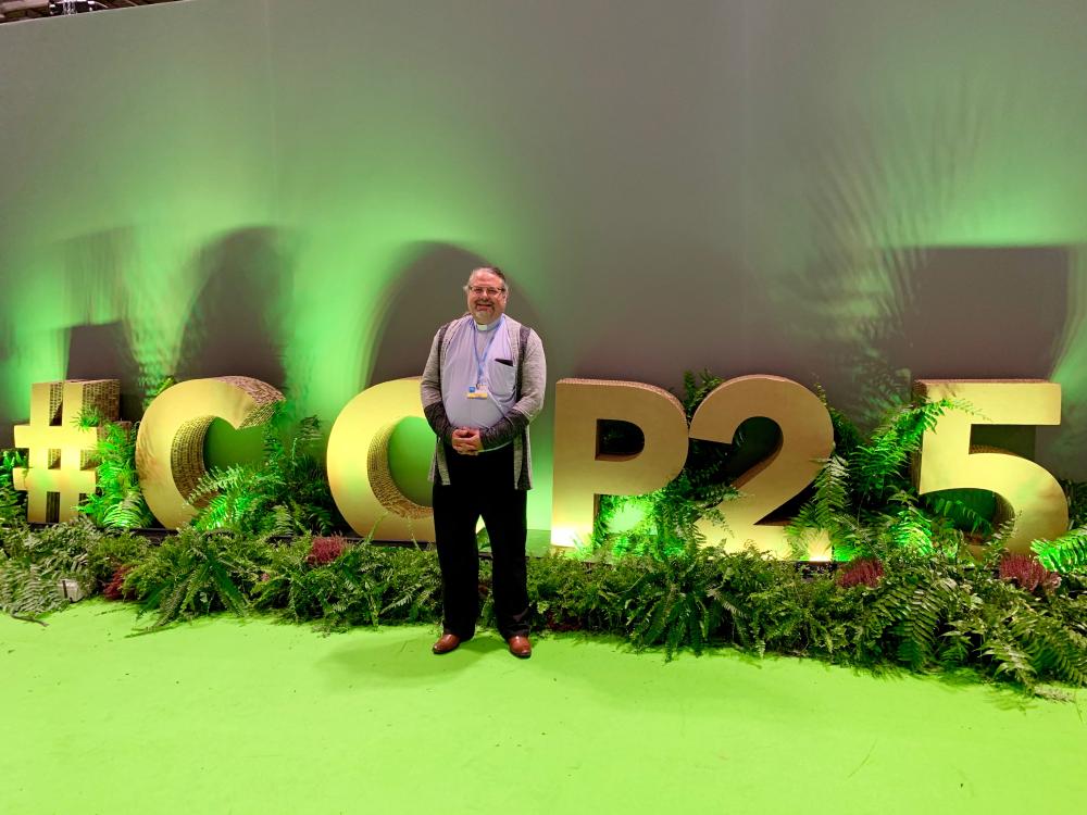 man stands in front of big letters that read COP25