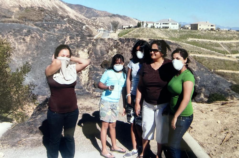 a woman and her family stand outside wearing cloths over their mouths and noses