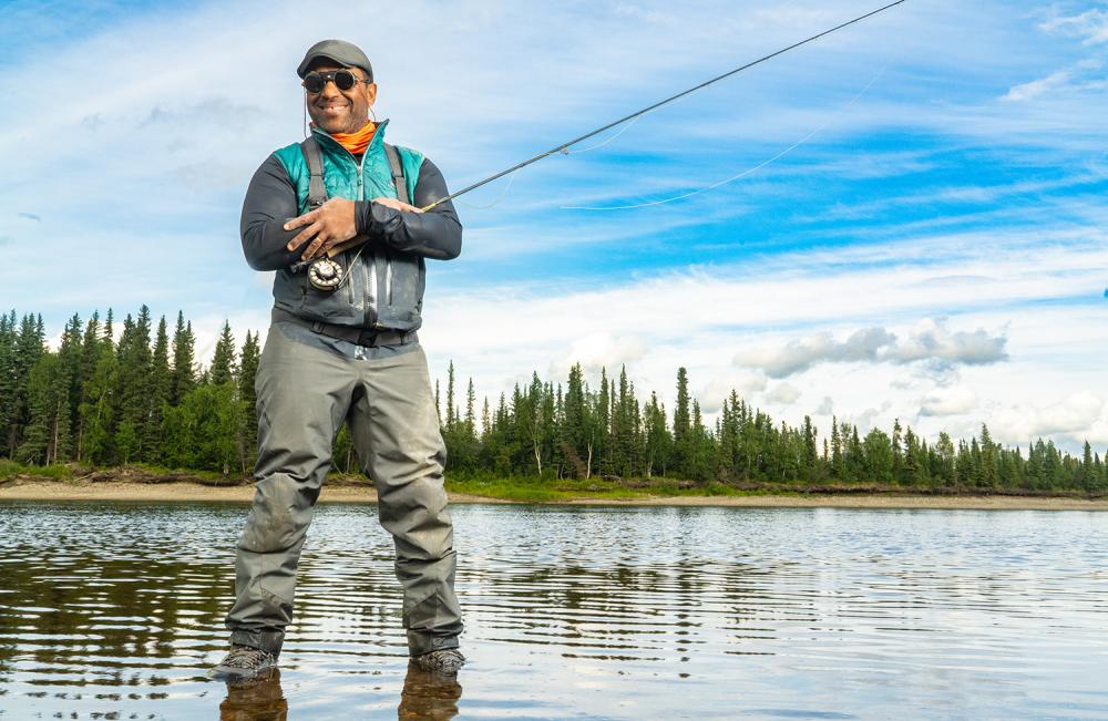 Man smiling standing on a lake, while holding a fishing pole