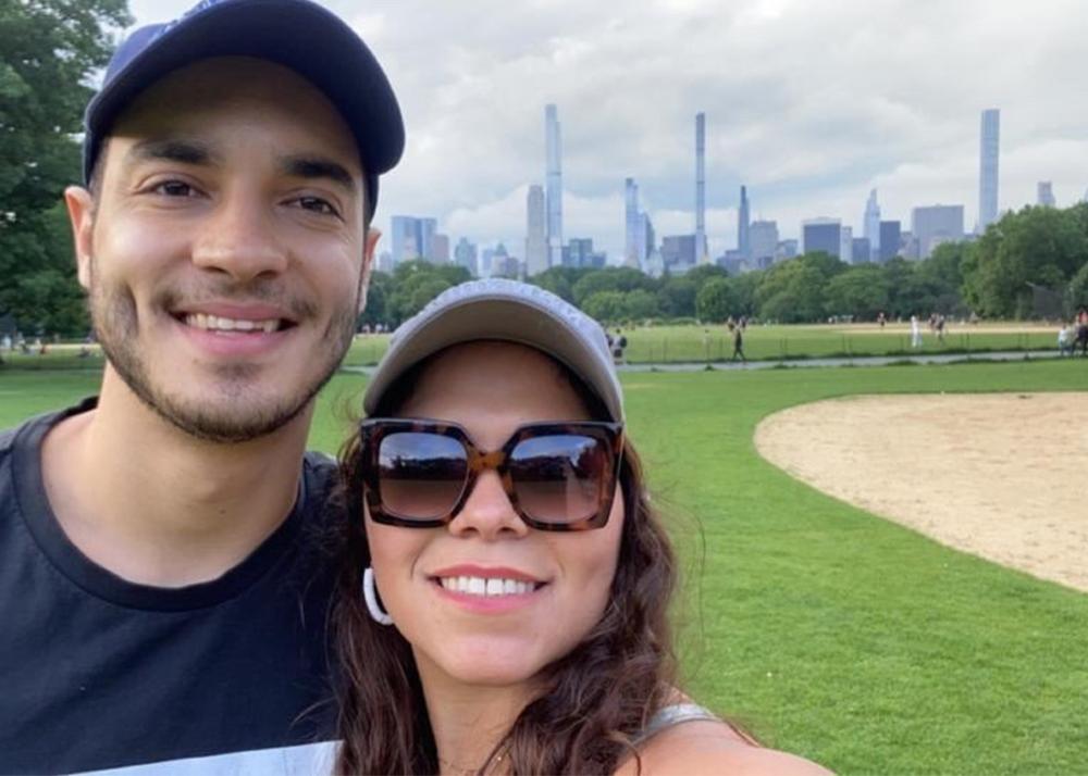couple posing for a selfie on a park, with city landscape in the background
