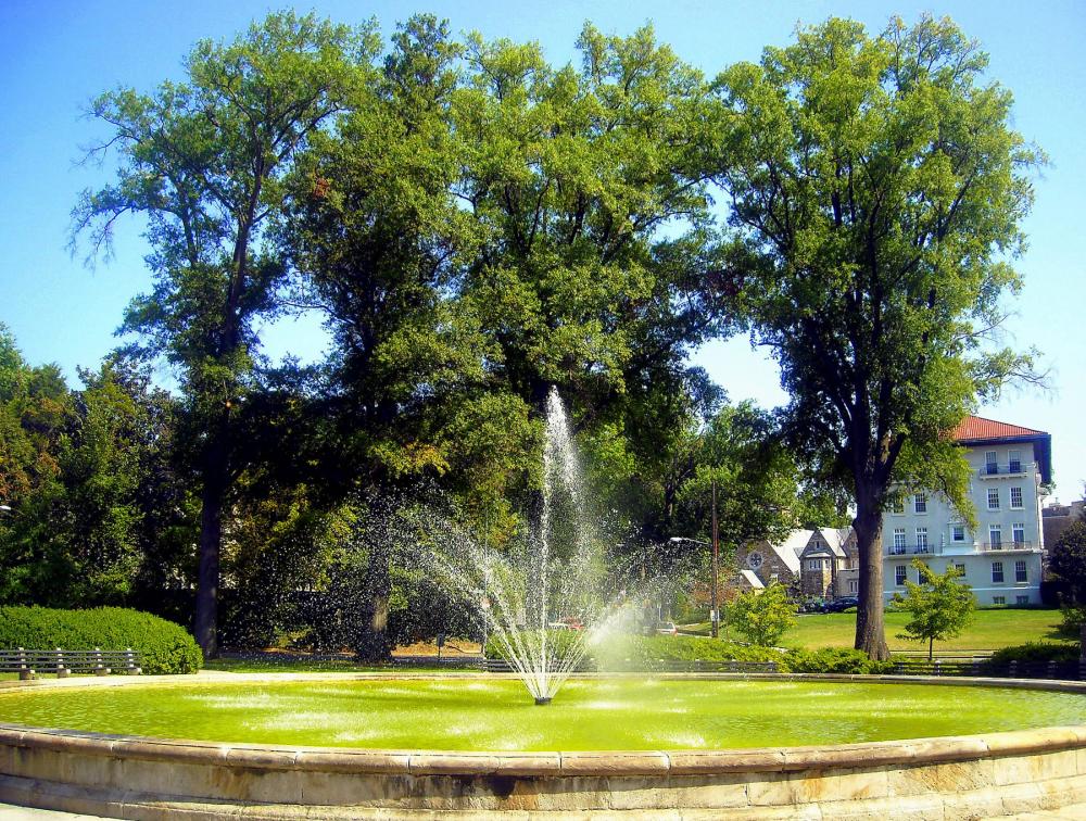 Founting spraying water in the middle of a verdant circle with trees in the background, in Chevy Chase on the border between Maryland and Washington, DC