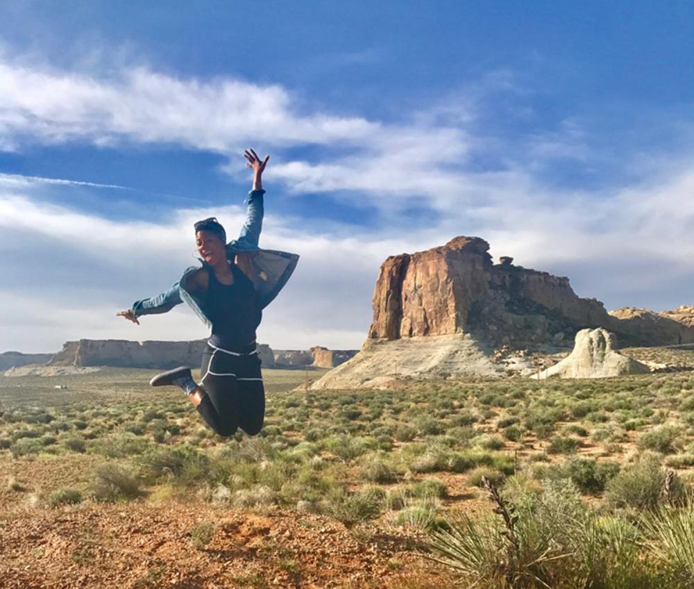 Woman jumping over a massive landscape and a canyon in the background