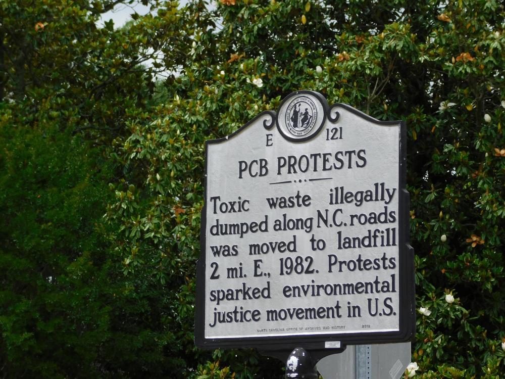 Historic marker reading "PCB Protests: Toxic waste illegally dumped along NC roads was moved to landfill 2 mi E, 1982. Protests sparked environmental justice movement in U.S."