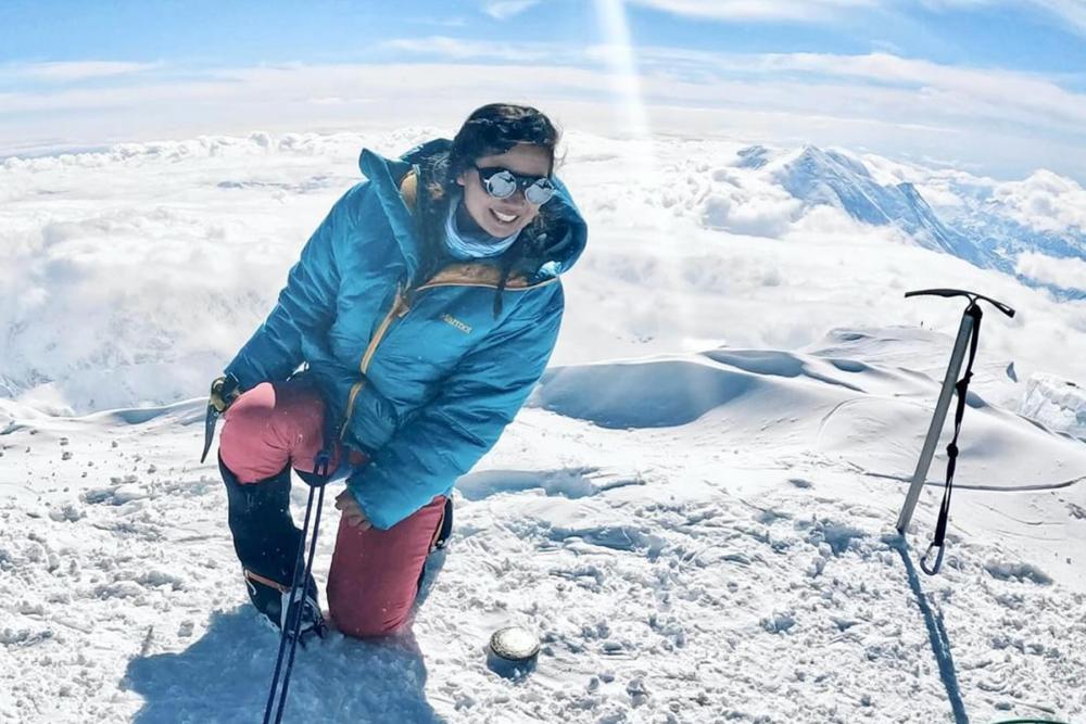 Woman with cold weather clothing smiling while surrounded by snow