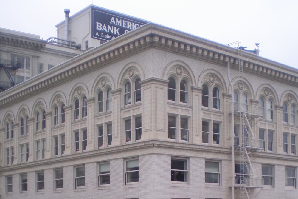 A diagonal view of the top three floors of a large beige building. There is elaborate detailing around the windows on the top two floors.