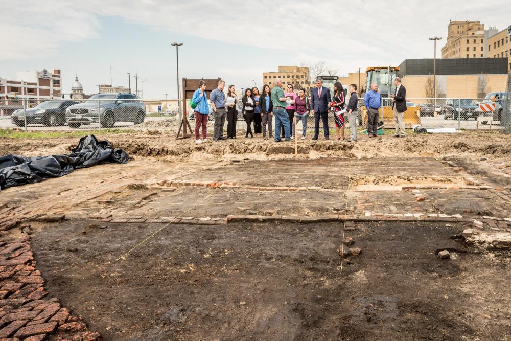 people gathering behind an excavation site. 