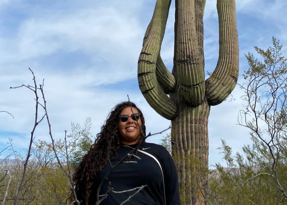 woman smiling and standing in front of a saguaro