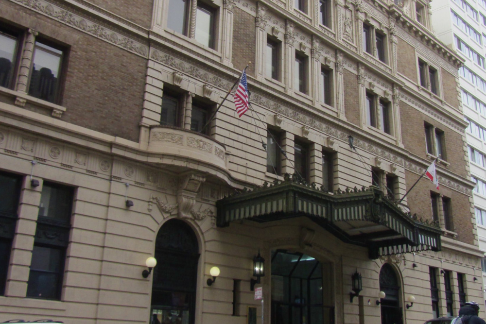 street view of California Hall, a large building on Polk Street in San Francisco. The light brown building has a marquis and detailed columns. 