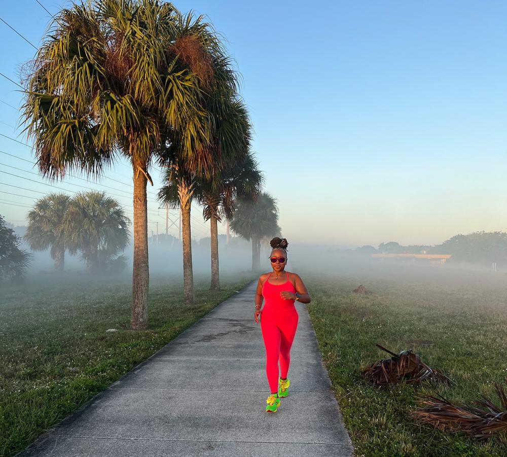 Woman with bright colored clothing running with palm trees on the left side