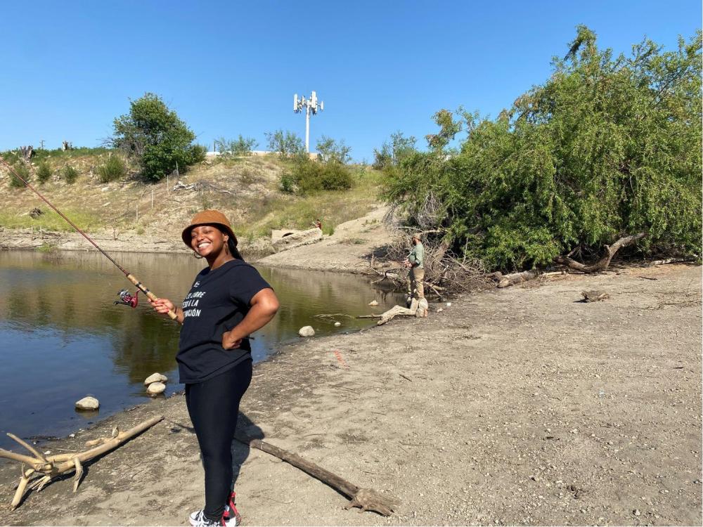 Sharon is fishing in front of a pond.