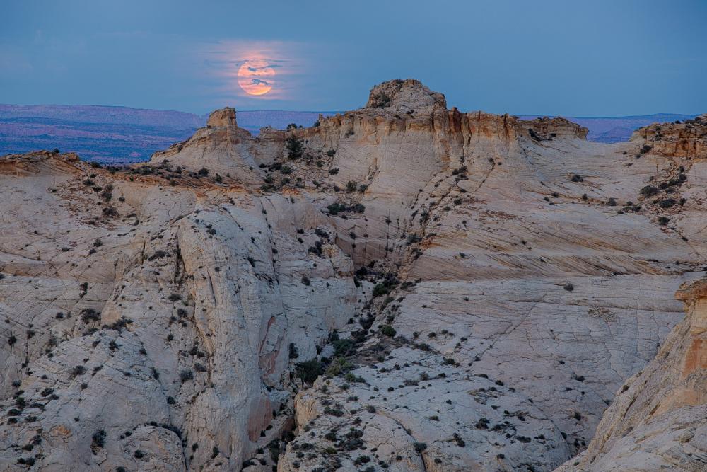 Full moon setting behind cliffs in Grand Staircase-Escalante National Monument, Utah.
