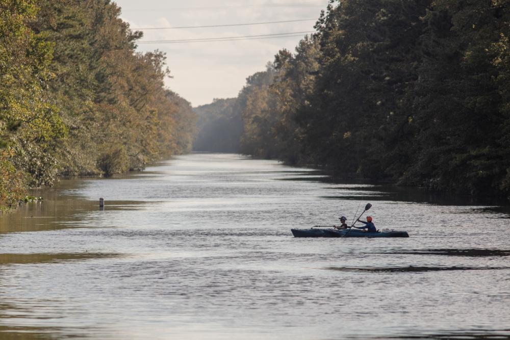 Two people canoeing across a river in the Great Dismal Swamp