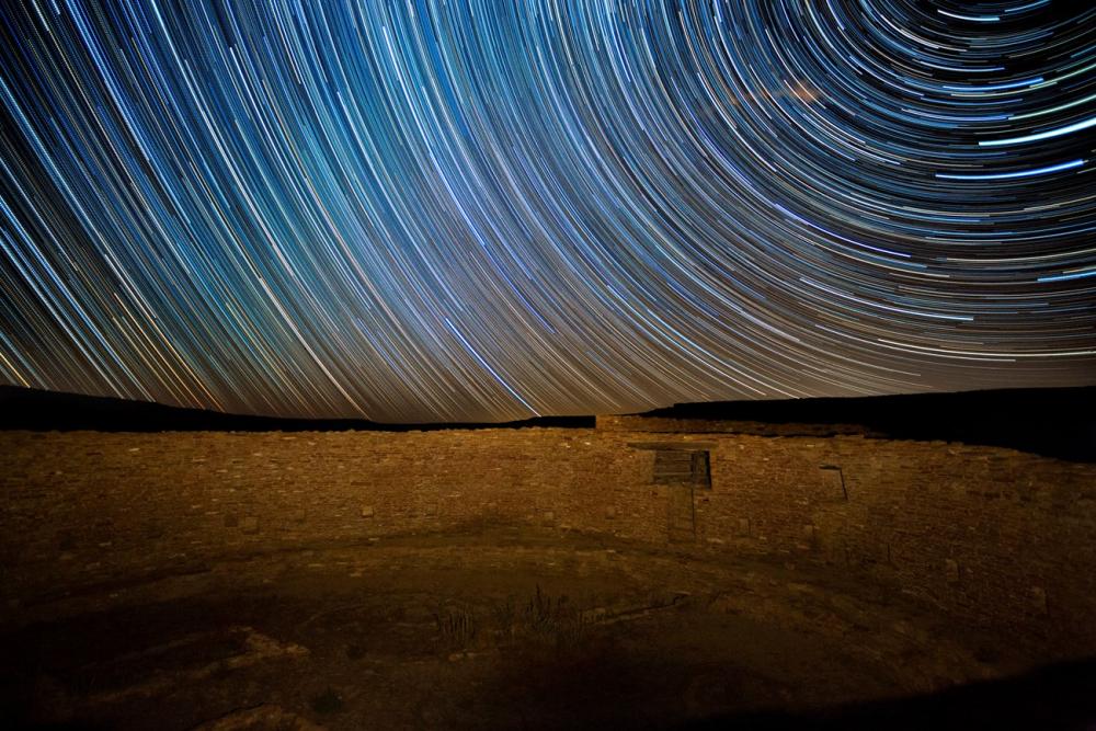 timelapse picture of stars over rock monument