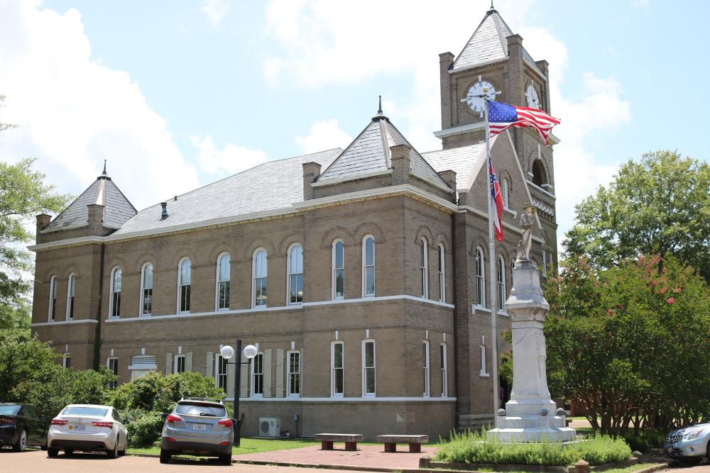 Two-floor brick structure with a clock tower, and an American Flag 