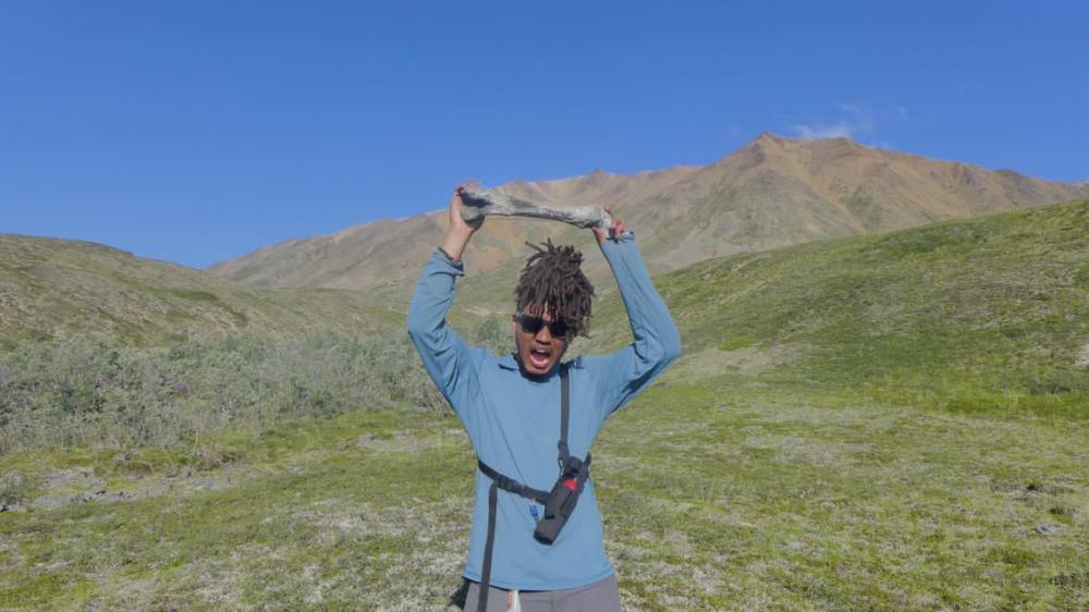 person holding a fossil over their head surrounded by greenery