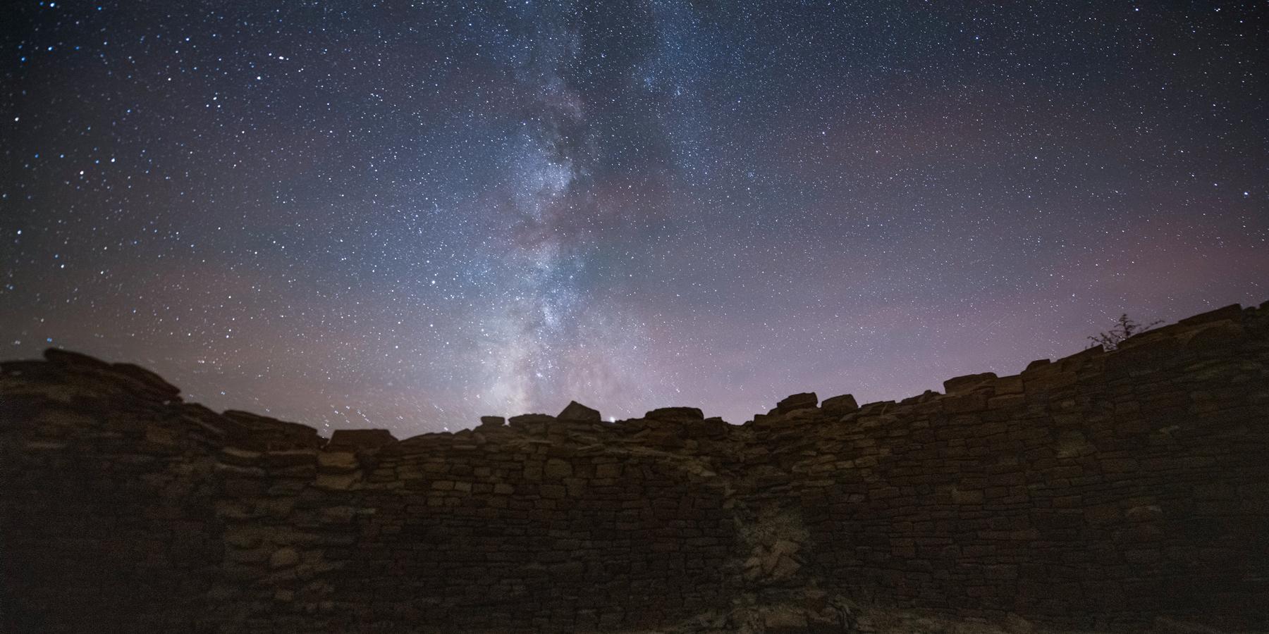 Remnants of stone wall underneath starry night sky