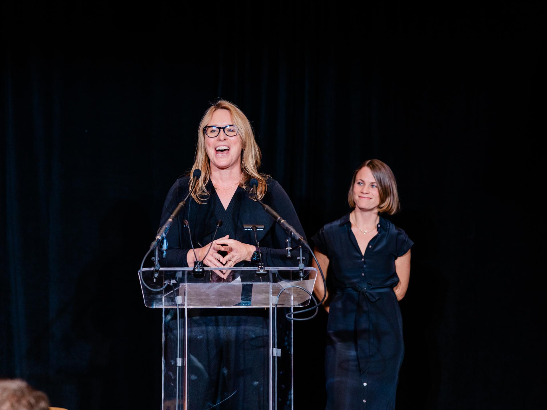 closeup of two women talking on a podium 