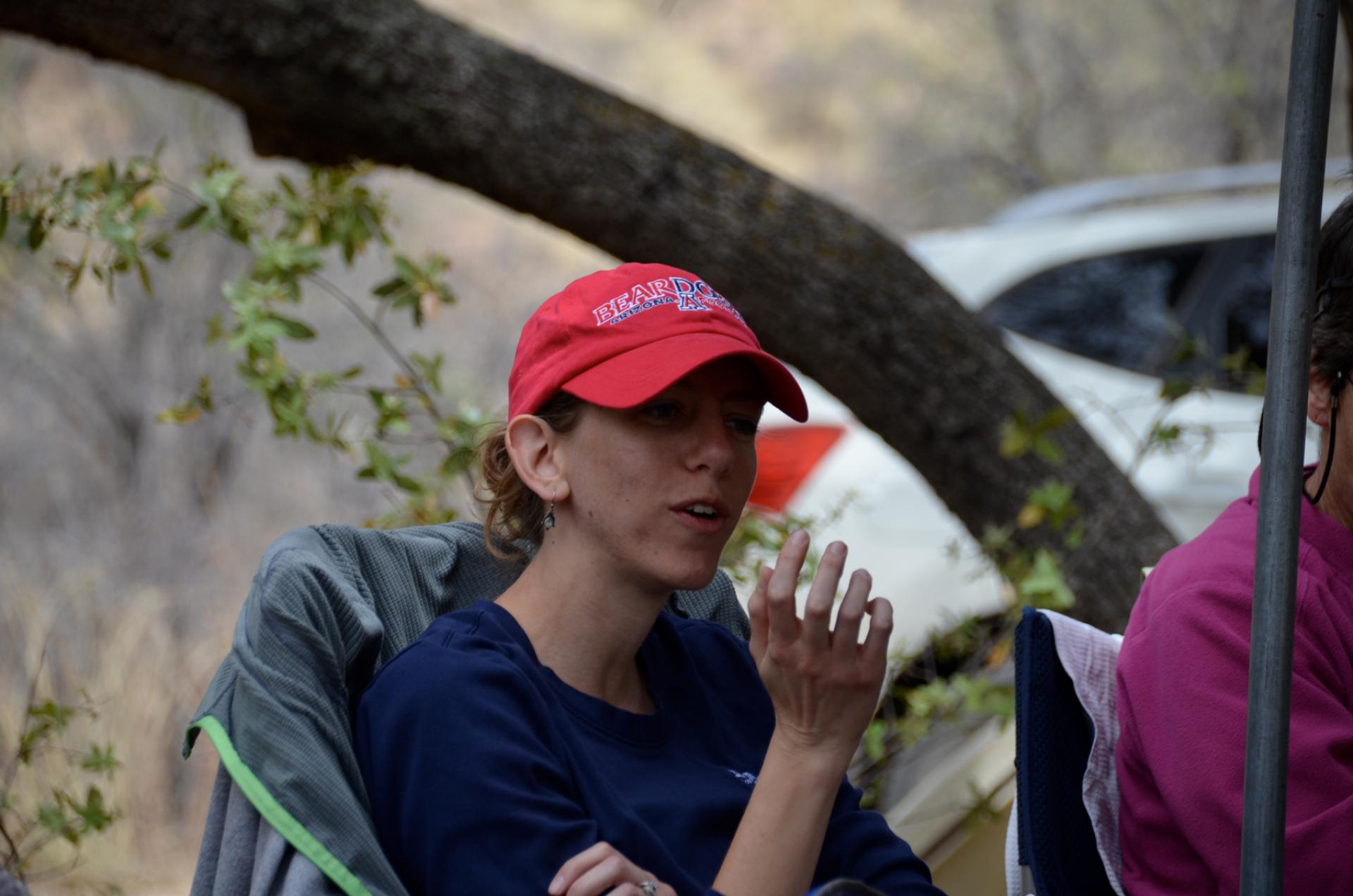 Woman with baseball cap sitting and talking under canopy