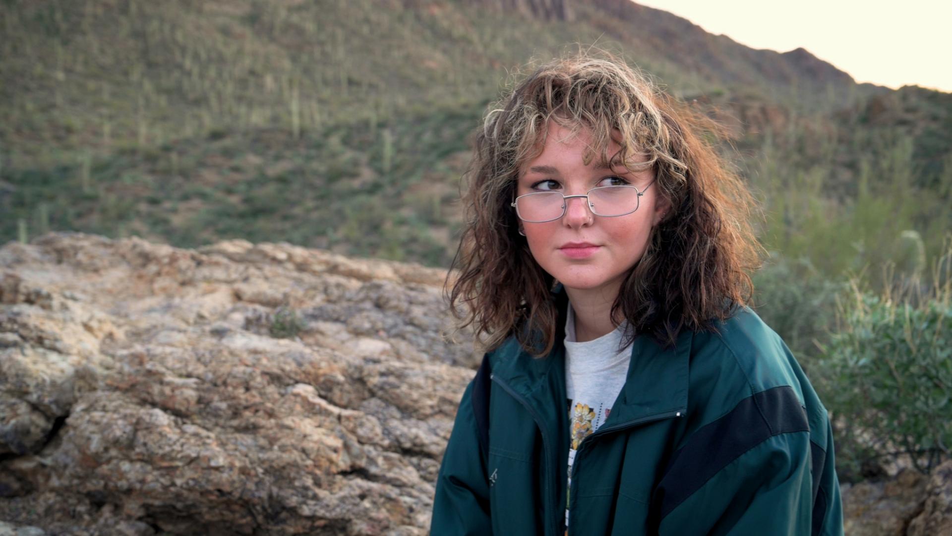 Person facing camera with desert terrain behind them