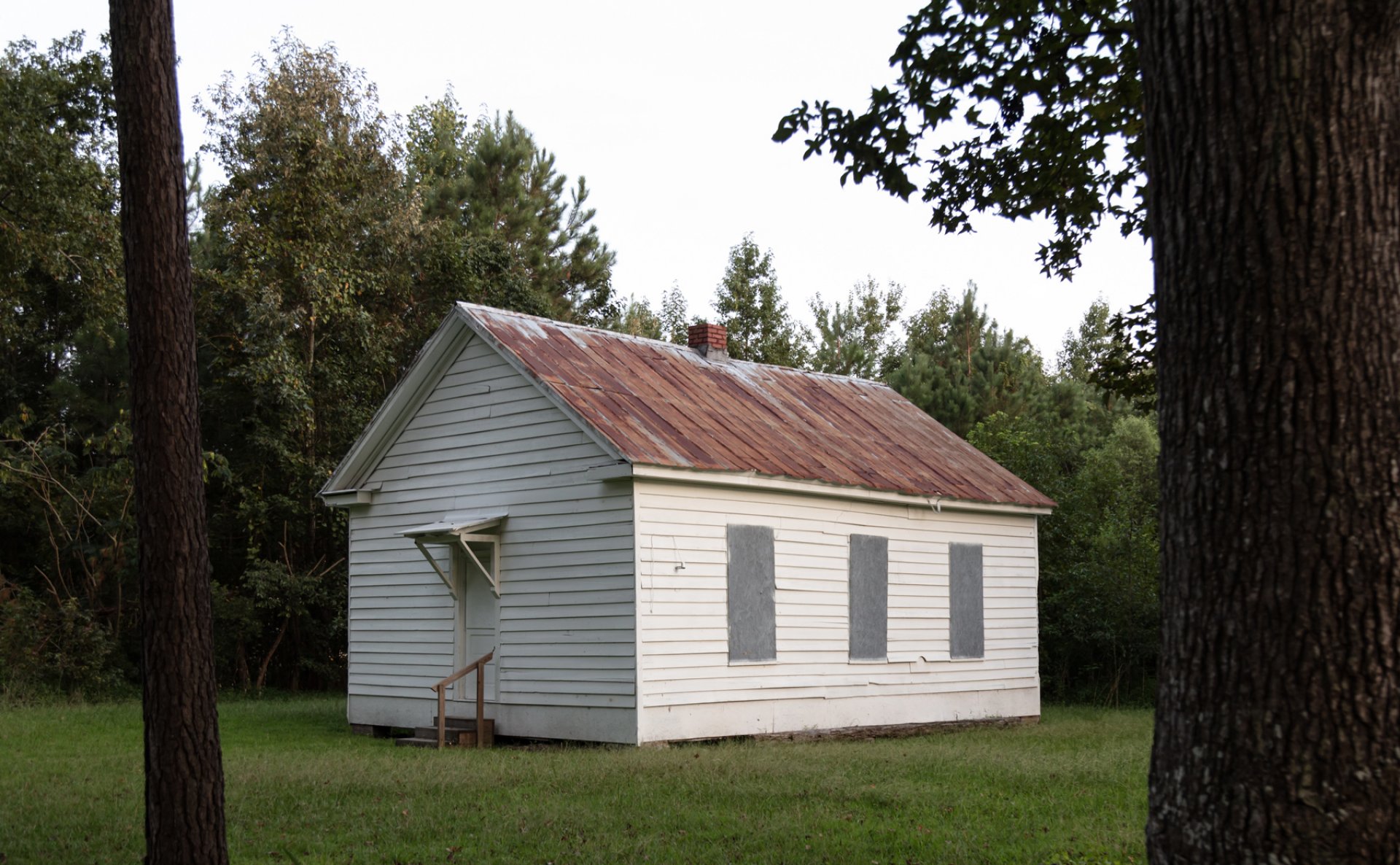 Small one-room schoolhouse in a clearing with trees behind it near Great Dismal Swamp, Virginia