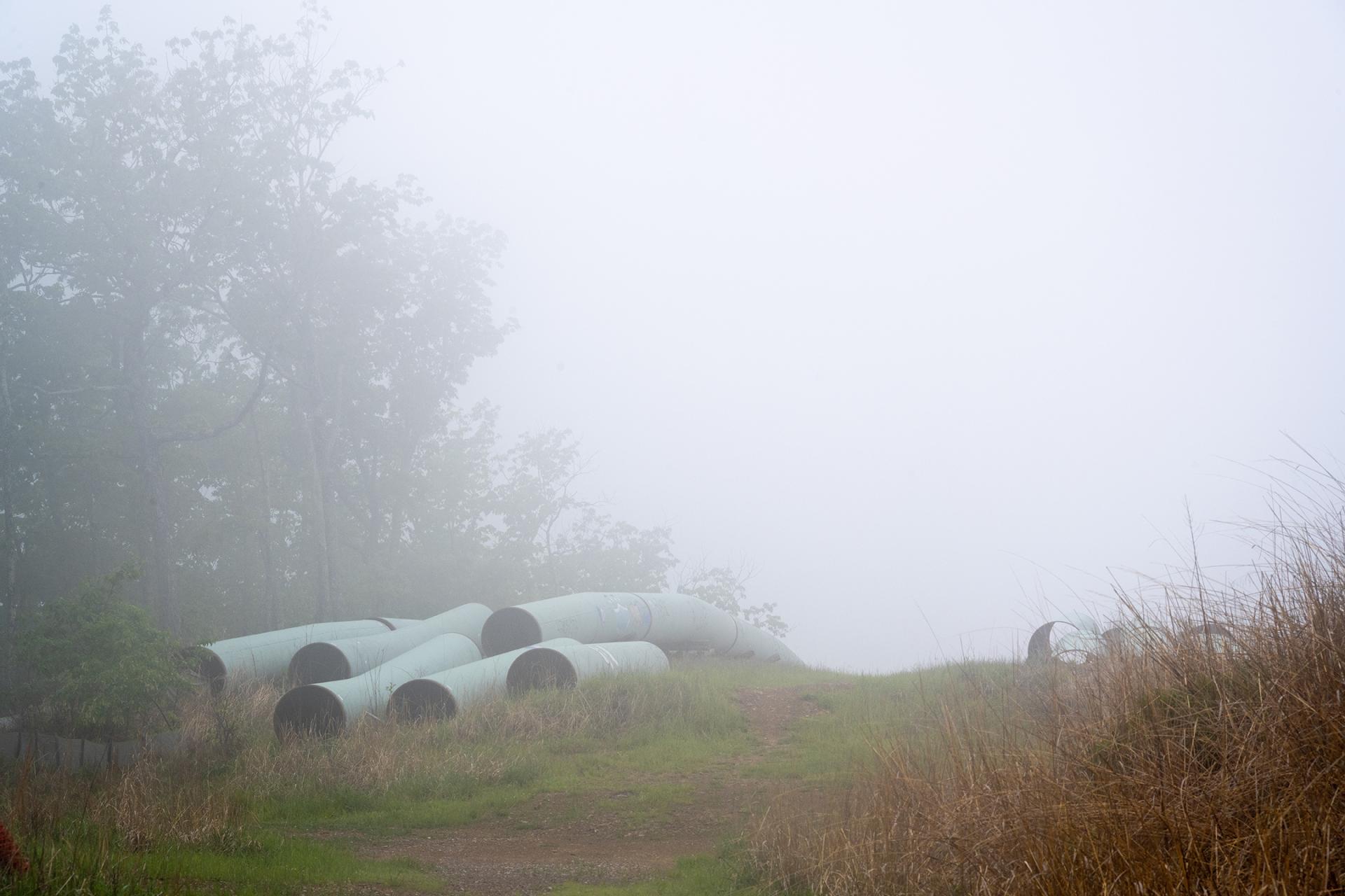 Pipeline pieces stacked on a foggy hillside in the Jefferson National Forest.