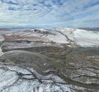 Aerial view of river with snow-fringed mountains in the background