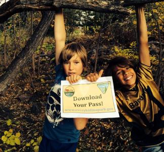 Two kids hold a sign reading "Download Your Pass" at an Every Kid in a Park event in 2015, Lakewood, Colorado