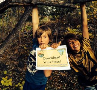 Two kids hold a sign reading "Download Your Pass" at an Every Kid in a Park event in 2015, Lakewood, Colorado