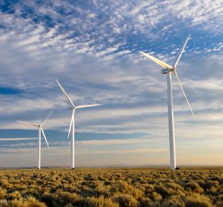 Three wind turbines against a blue sky with sparse clouds.