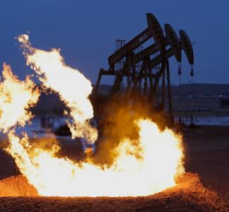 A flame pit sits in front of an oil and gas well