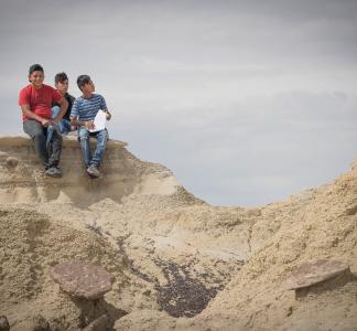 Three teenagers sit on a rock formation at Ah-Shi-Sle-Pah Wilderness Study Area, New Mexico