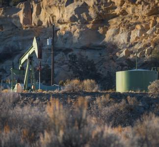 Pump jack and other oil and gas extraction equipment in a rocky desert landscape