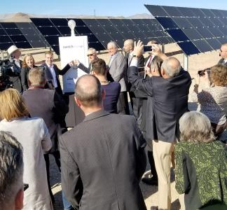 Crowd of people viewed from behind in foreground, former Sen. Harry Reid in background flipping "on" switch at the Dry Lake Solar Energy Zone in Nevada