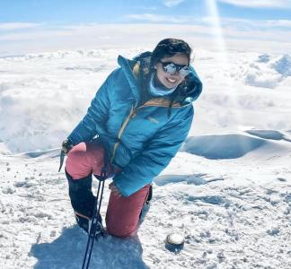 Woman with cold weather clothing smiling while surrounded by snow