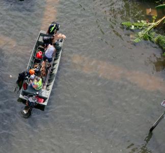 Aerial view of a people in a boat that's floating on brownish flood waters