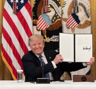 President Trump holding signed proclamation with an American flag over his right shoulder