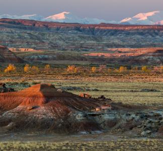 Multicolored buttes and plains landscape with snowcapped mountains in the background