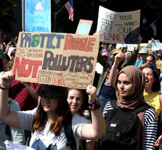 Women in foreground marching at rally and holding signs during Global Climate Strike in 2019 in Washington, DC 