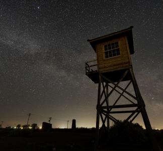 Tall Guard tower at night with stars and city lights behind