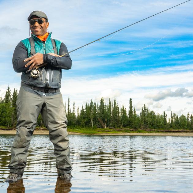 Man smiling standing on a lake, while holding a fishing pole