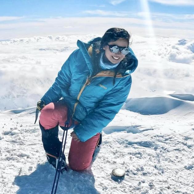 Woman with cold weather clothing smiling while surrounded by snow