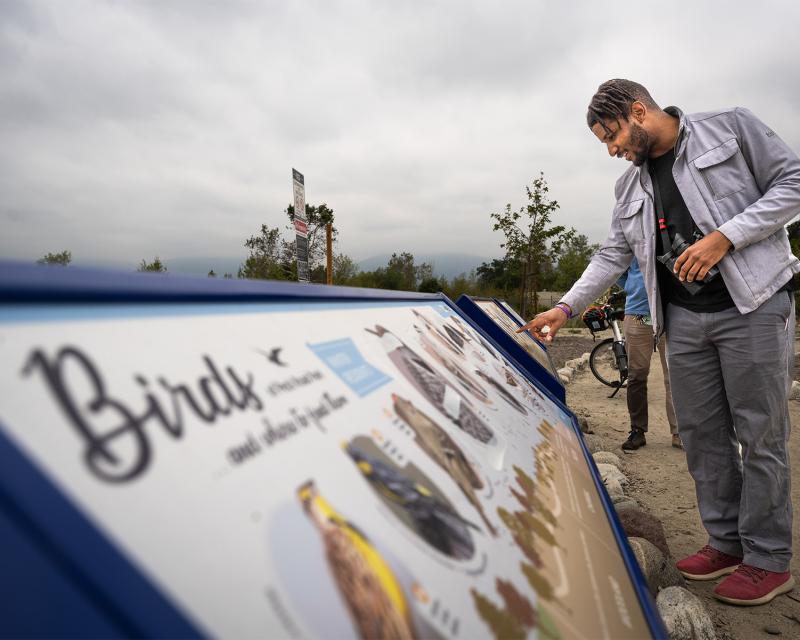 person with binoculars reading a sign about birding