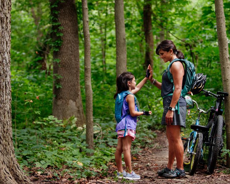 Child and biker give each other a high five in a park.