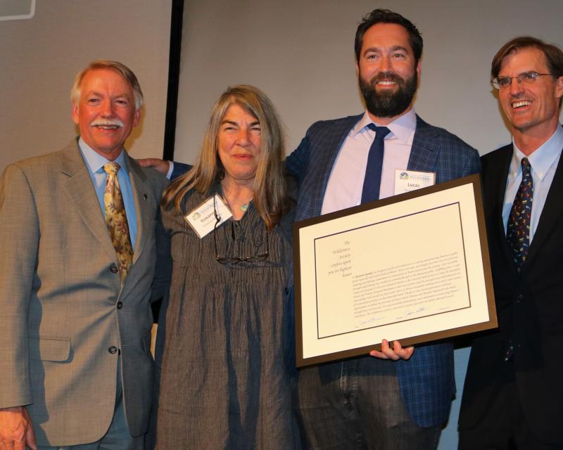 five people stand next to each other with the middle person holding a certificate